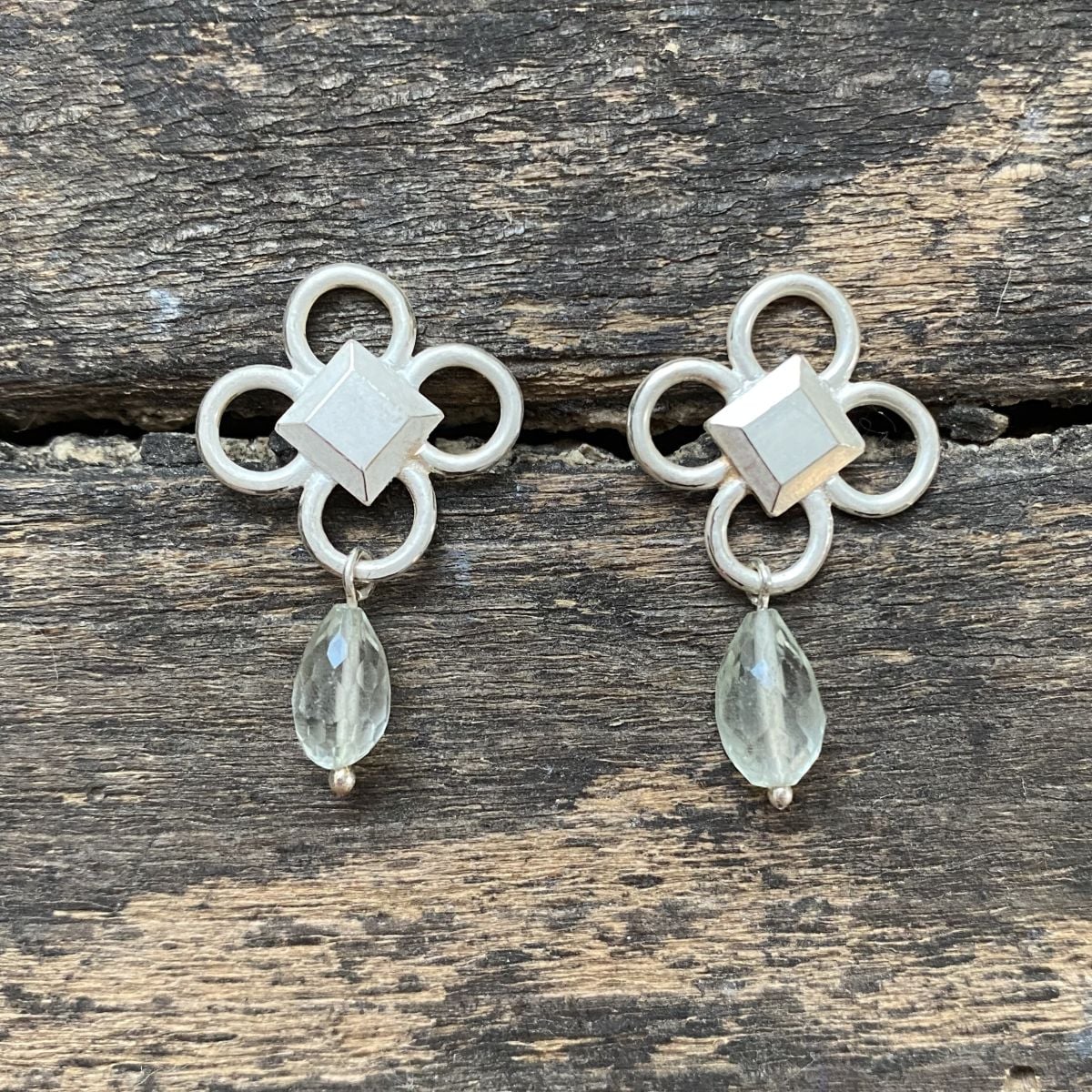Silver drop earrings on wooden background
