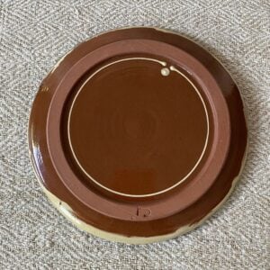 underneath of a glazed plate by Jennifer Hall on a cream cloth background