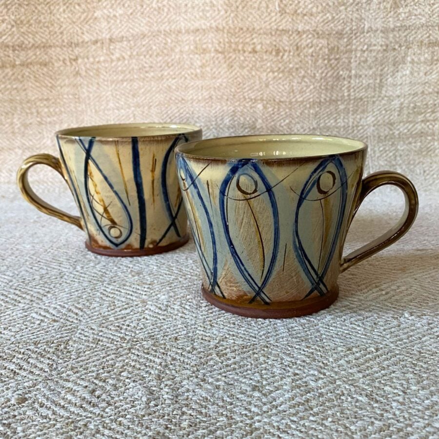 Jennifer Hall pair of slipware glazed tea mugs on a cream textile background