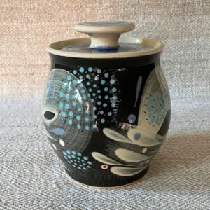 RAMP Ceramics earthenware caddy jar in a blue abstract design on a cream textile backdrop.