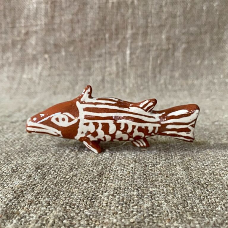 Emma Carlow pottery whistle in the shape of a FISH against a cloth backdrop