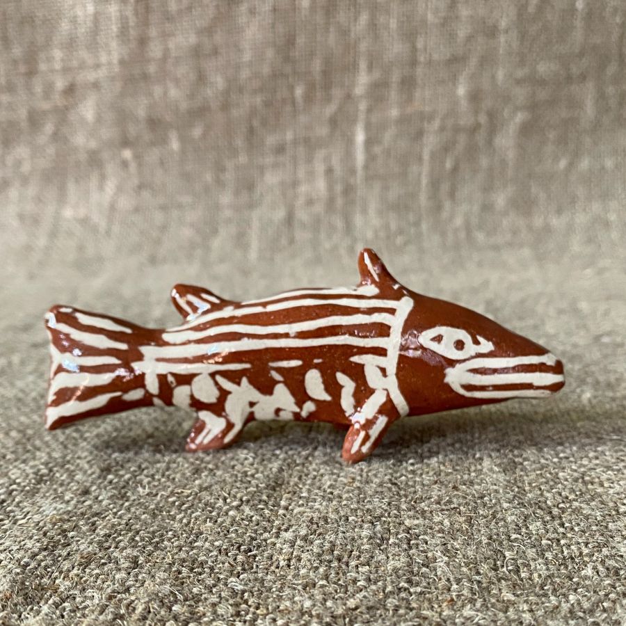 Emma Carlow pottery whistle in the shape of a FISH against a cloth backdrop